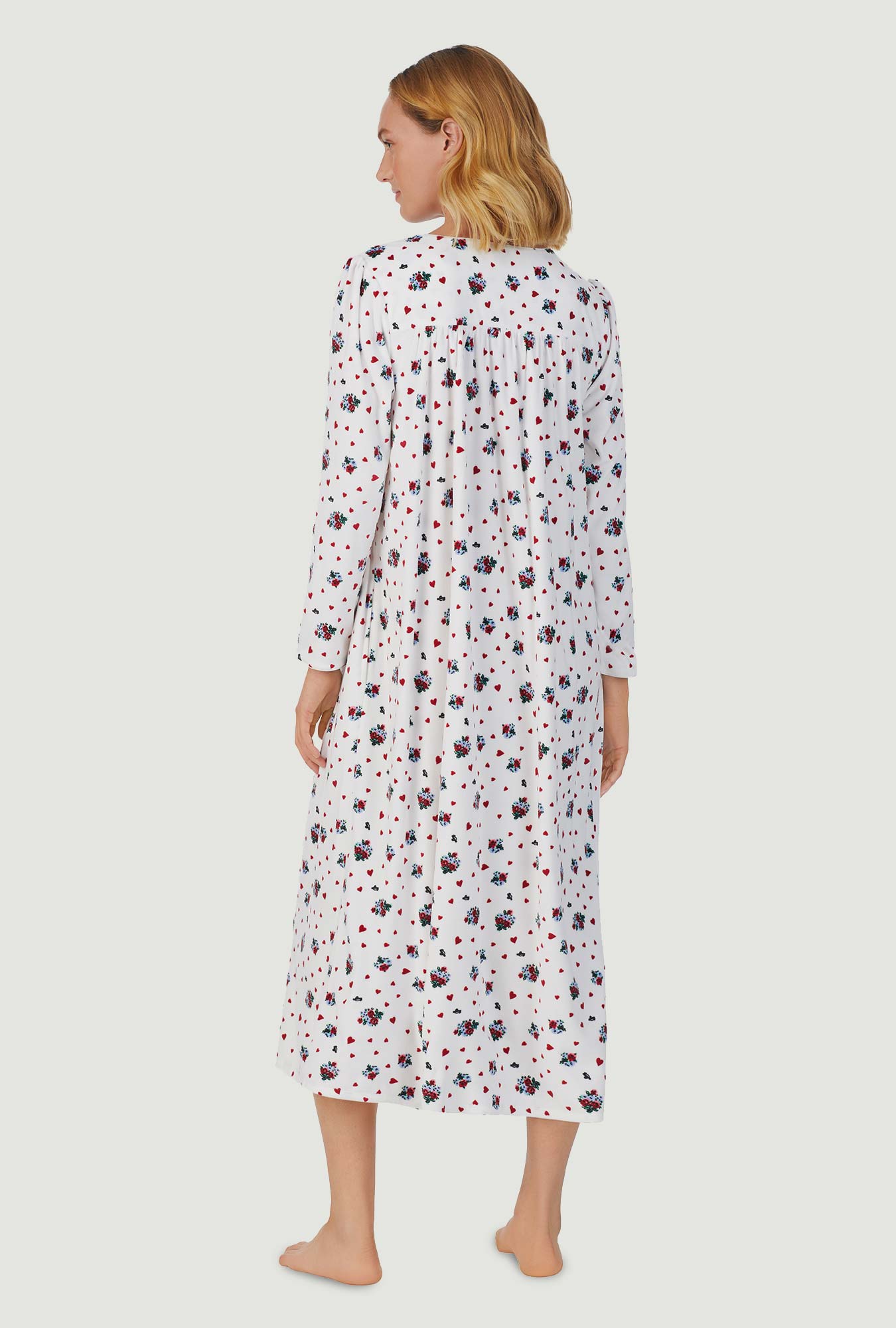 A lady wearing white long sleeve cozy fleece gown with heart floral print.
