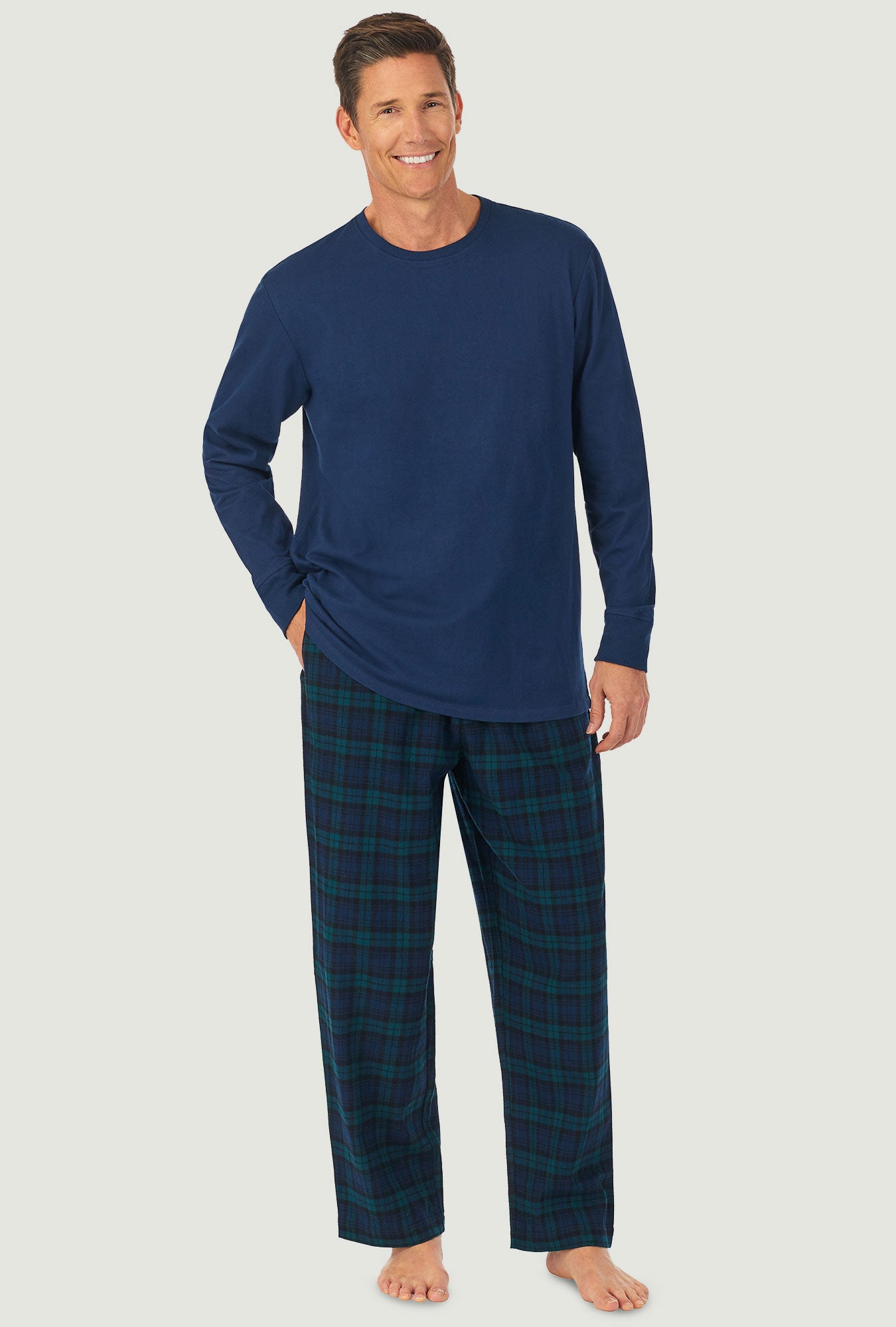 A man wearing a black watch plaid long sleeve men's knit and flannel pj set.