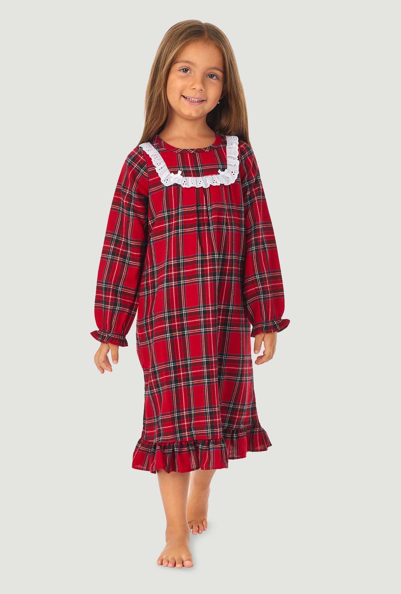 A girl wearing a red tartan long sleeve nightgown.