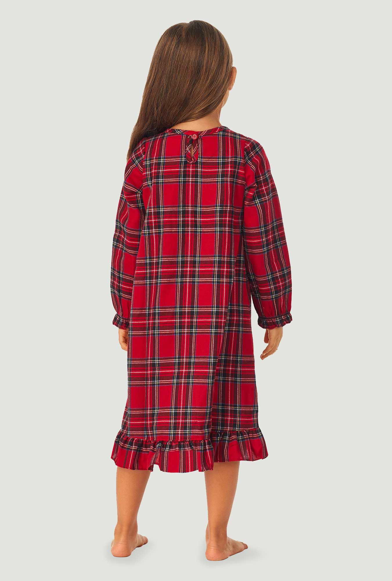 A girl wearing a red tartan long sleeve nightgown.