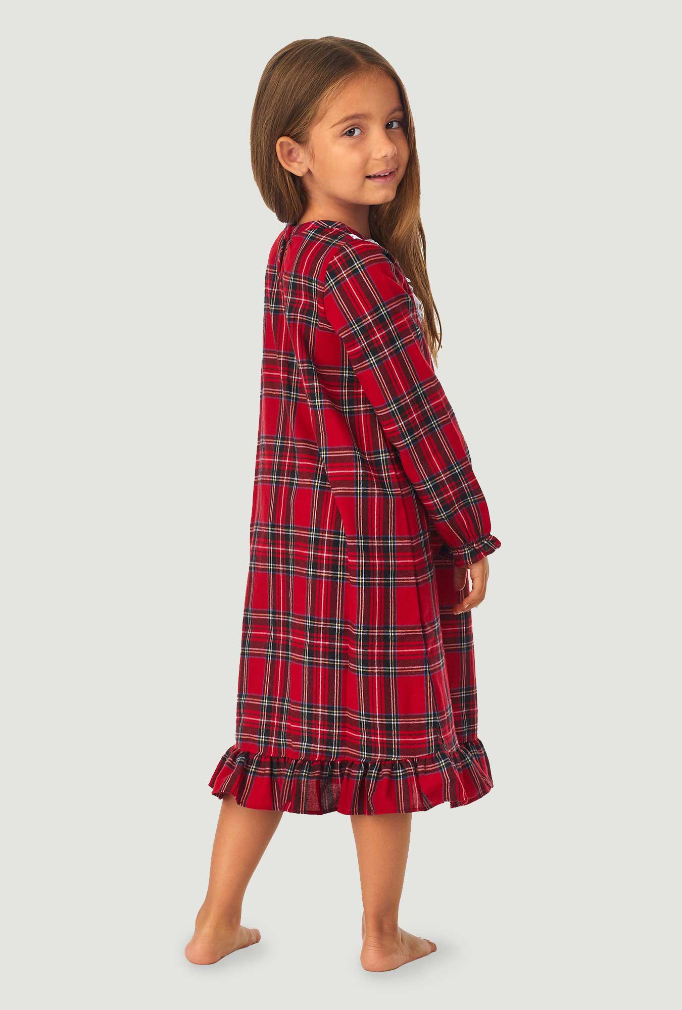 A girl wearing a red tartan long sleeve nightgown.