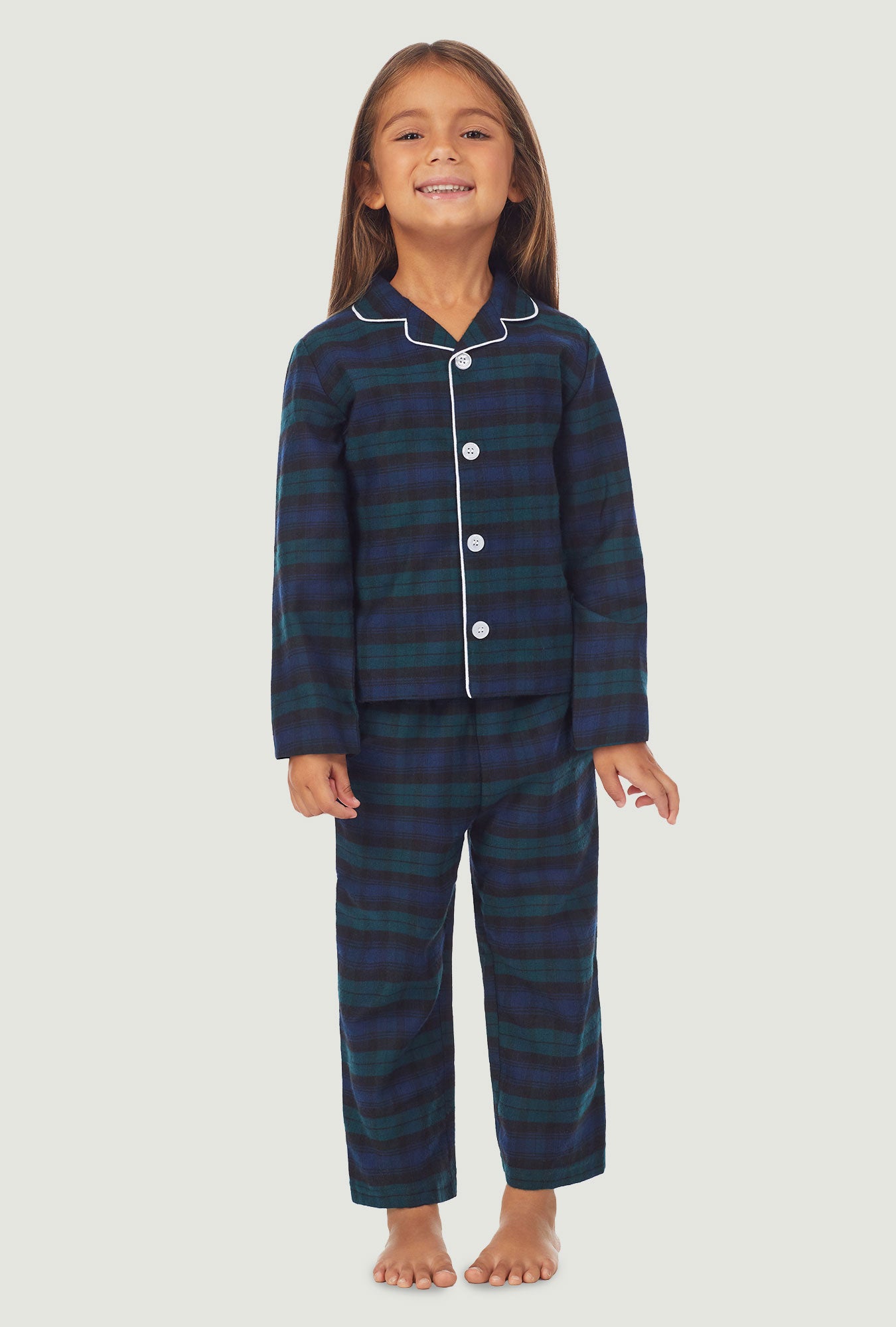A kid wearing a long sleeve pajama set with black watch plaid pattern.