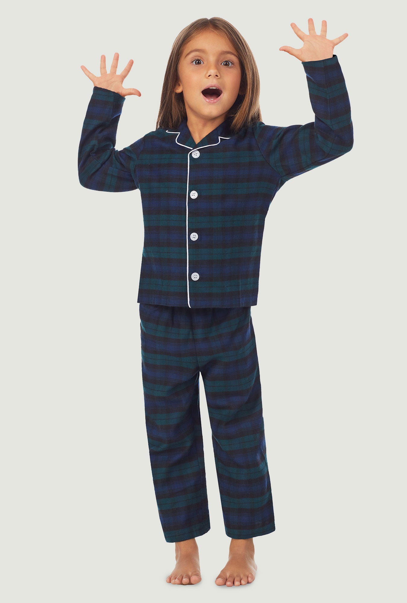 A kid wearing a long sleeve pajama set with black watch plaid pattern.