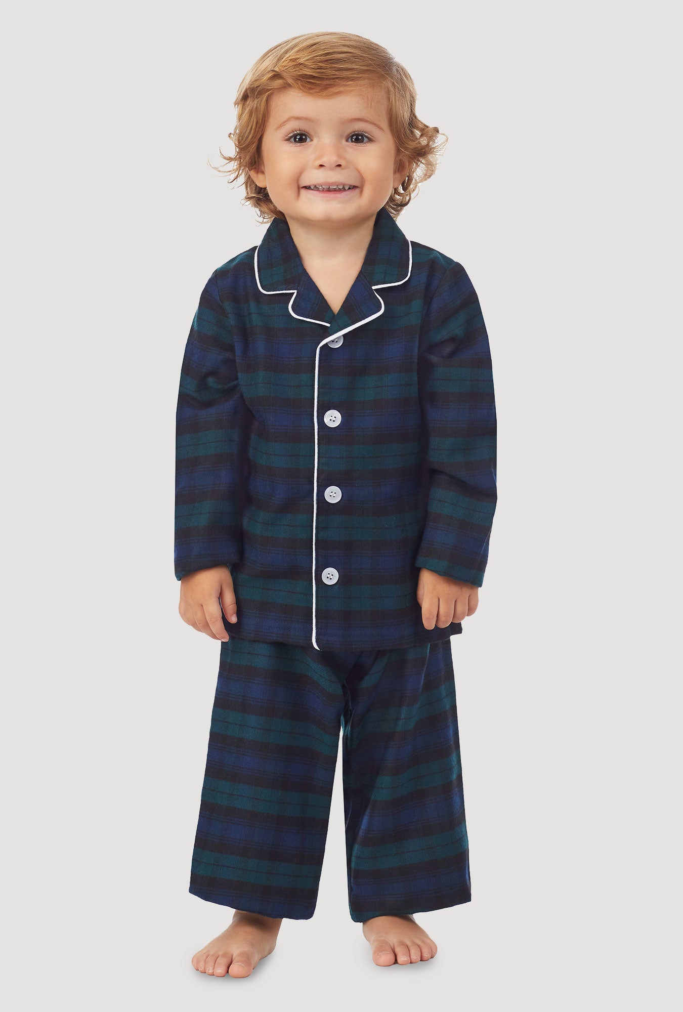 A kid wearing a long sleeve pajama set with black watch plaid pattern.