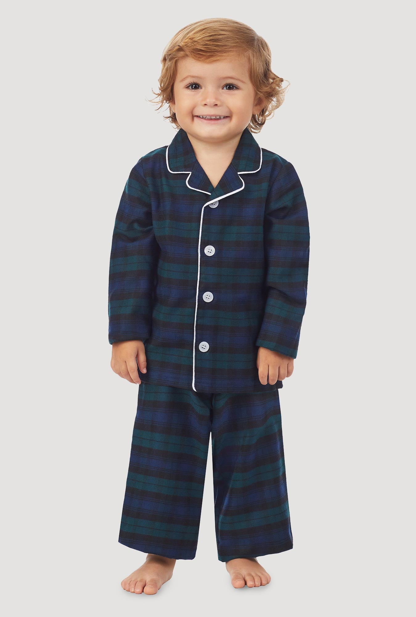 A kid wearing a long sleeve pajama set with black watch plaid pattern.