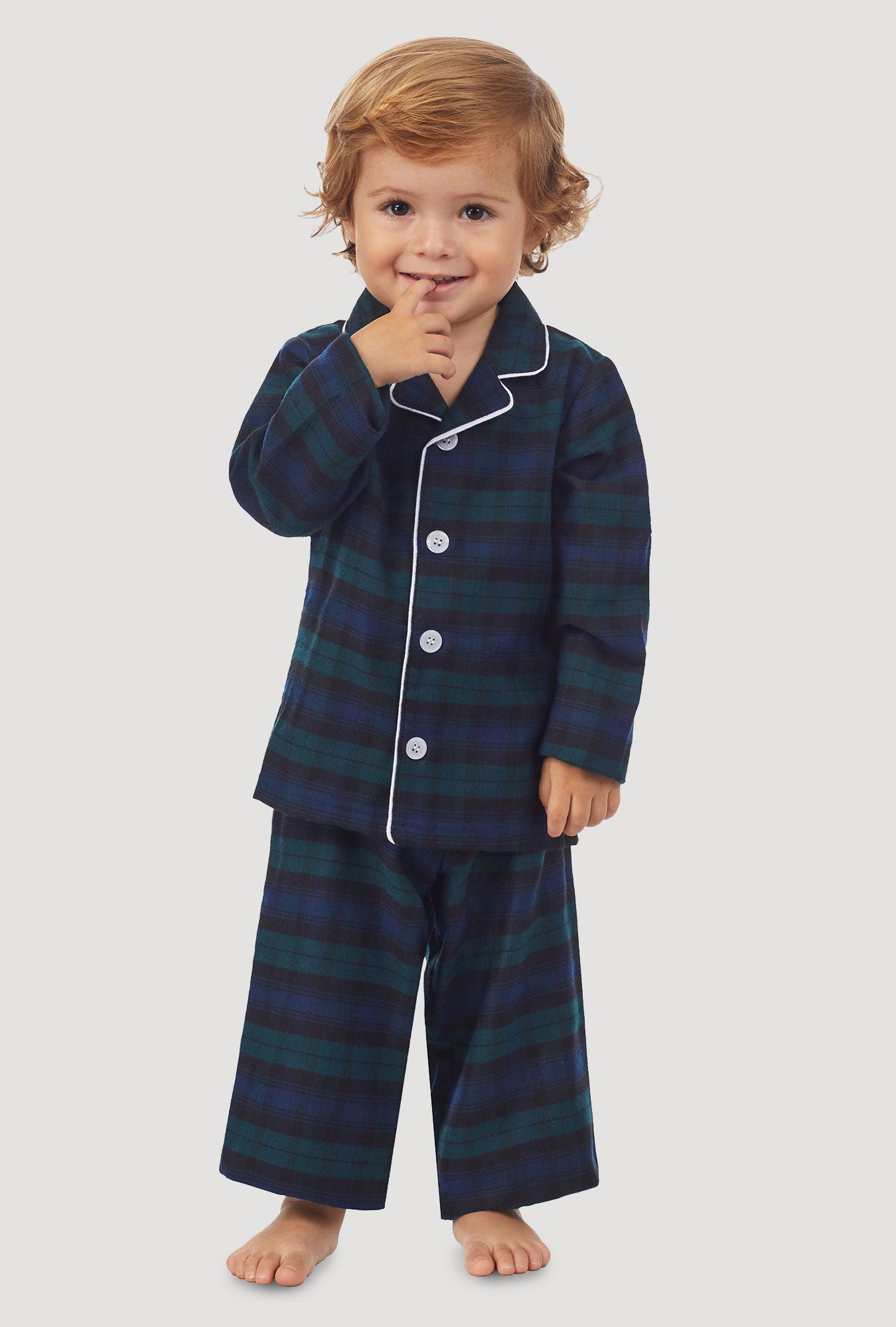 A kid wearing a long sleeve pajama set with black watch plaid pattern.