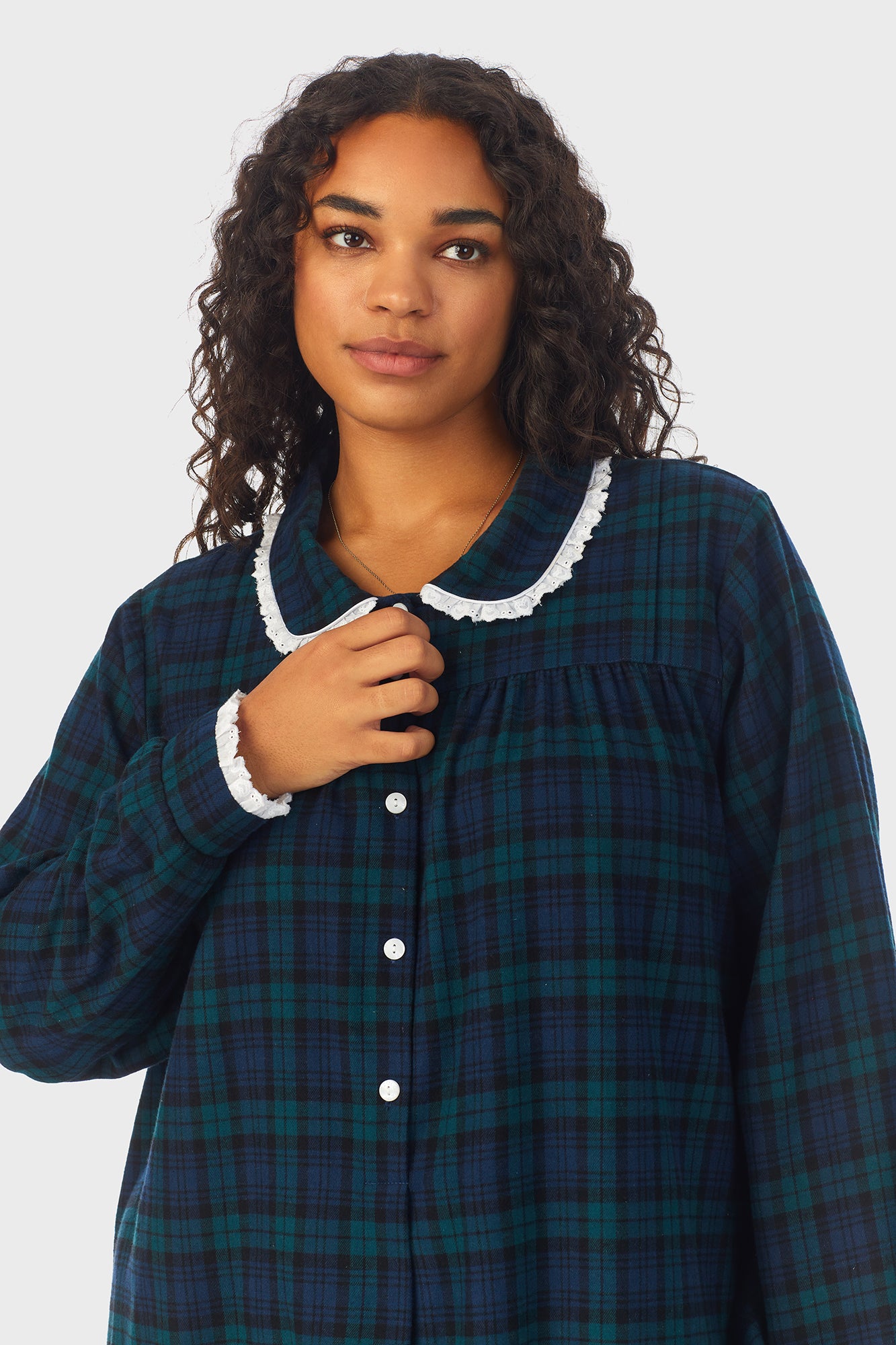 A lady wearing a long sleeve flannel gown plus with black watch peterpan pattern.