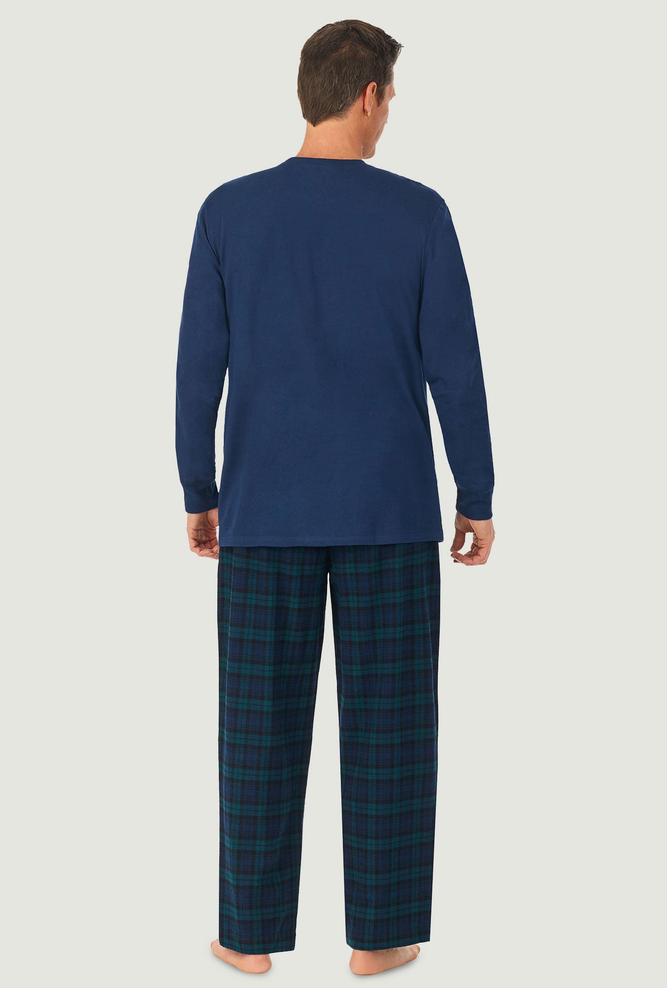 A man wearing a black watch plaid long sleeve men's knit and flannel pj set.