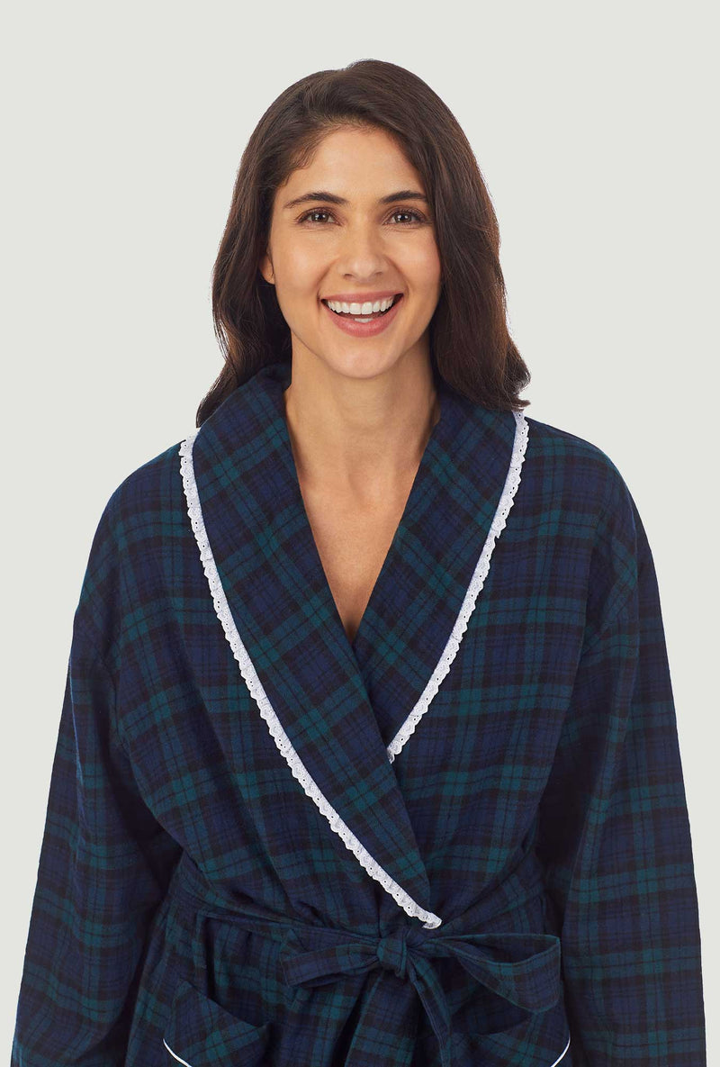 A lady wearing a long sleeve flannel robe with black watch plaid pattern.