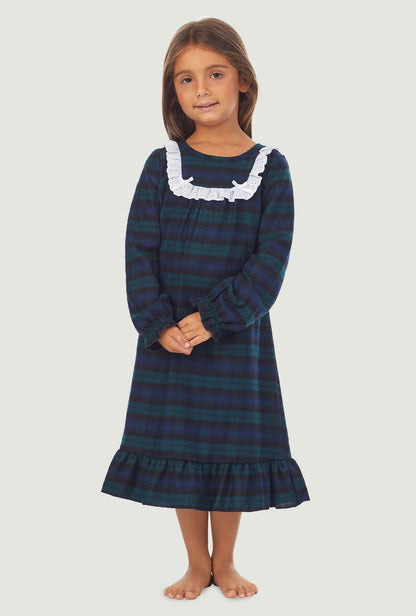 A girl wearing a black watch plaid long sleeve nightgown.