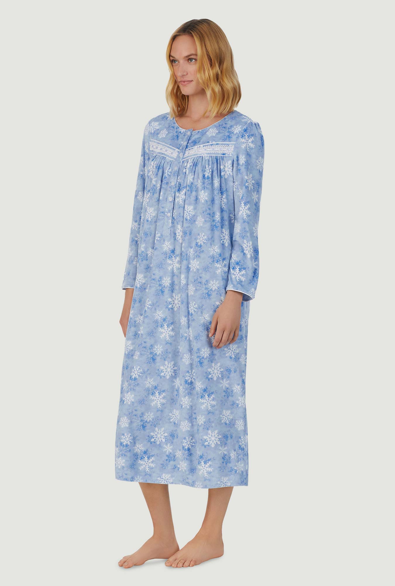 A lady wearing blue long sleeve cozy  fleece gown with snowflake wonderland print.