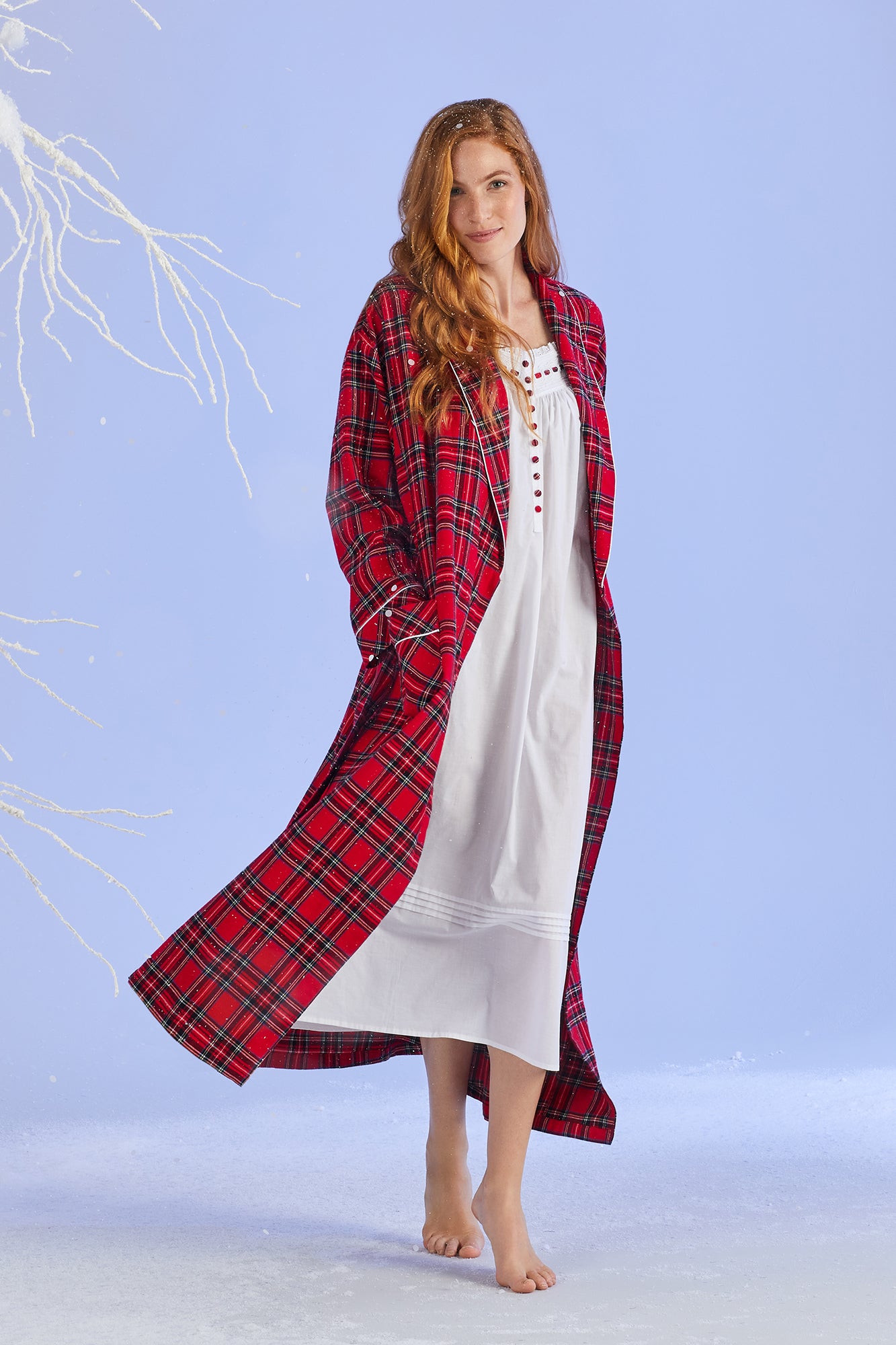 A lady wearing a white sleeveless cotton and red tartan nightgown.