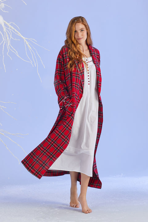 A lady wearing a white cotton and red tartan long sleeve nightgown.
