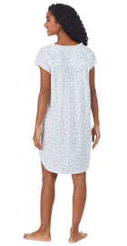A lady wearing a cap sleeve short nightie with tulip pattern.