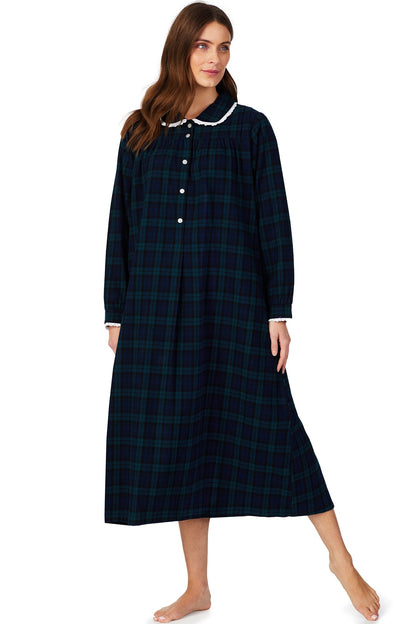 A lady wearing a long sleeve flannel gown petite with black watch plaid  pattern.
